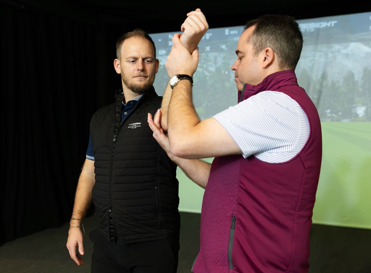 Rick Silva hands-on, assessing a player's arm movement during a physical screen